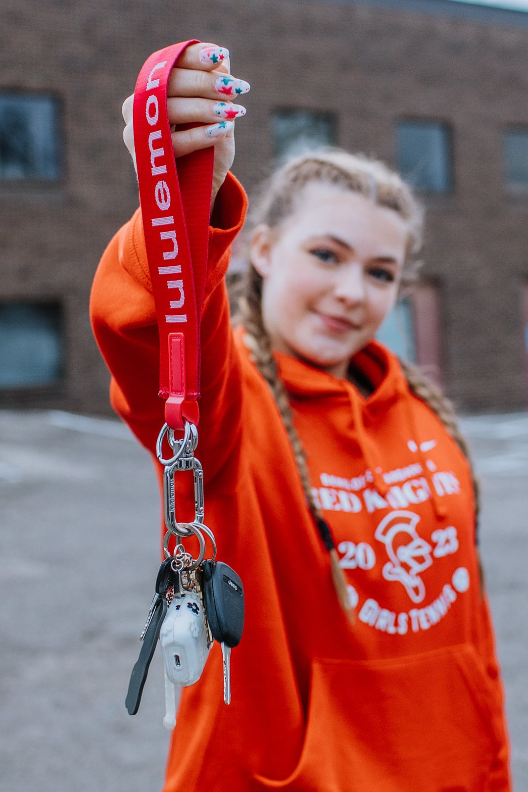 Group of ten high school driver's education students standing together in parking lot wearing college sweatshirts