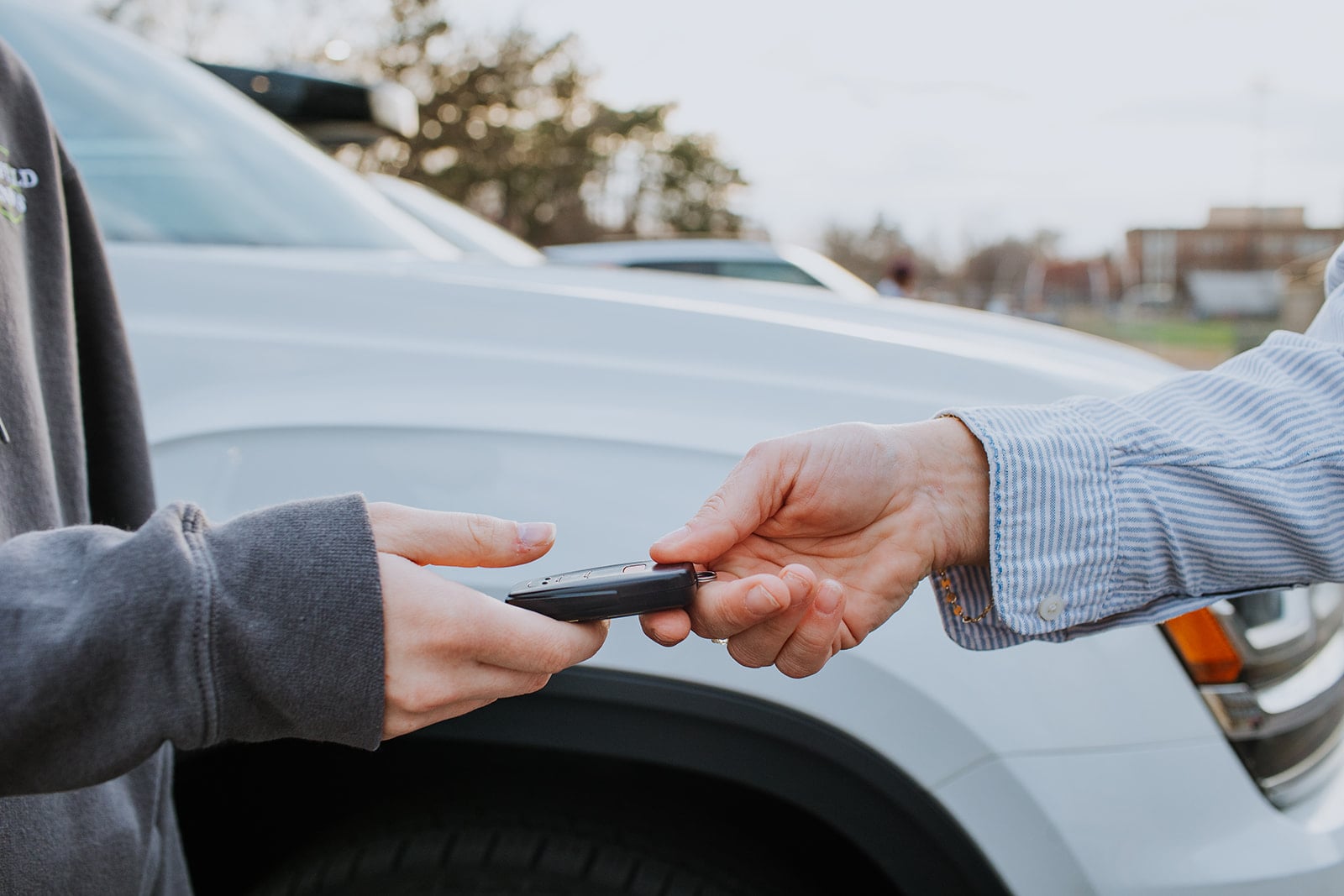 Group of ten high school driver's education students standing together in parking lot wearing college sweatshirts